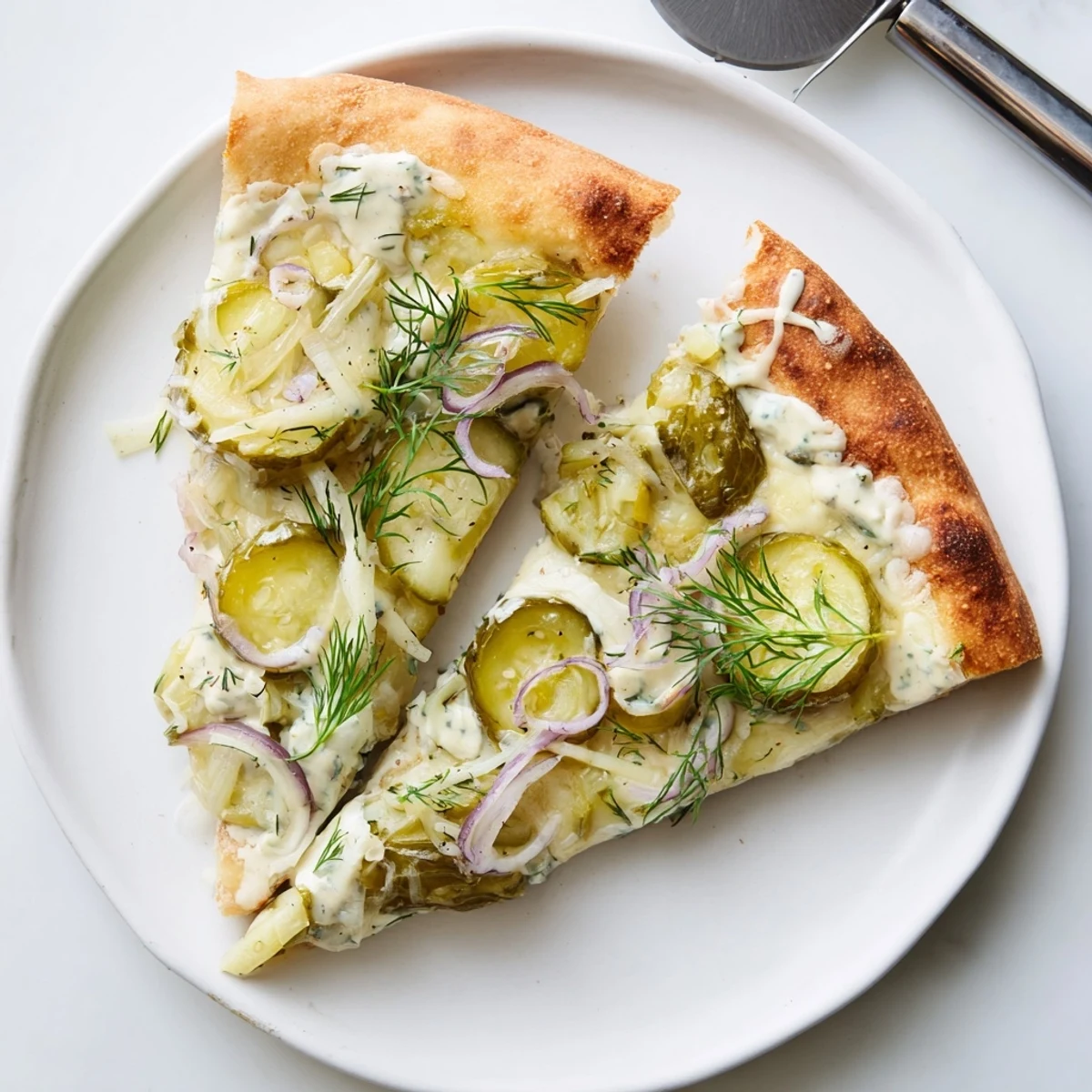 Savory pickle pizza with fresh dill, garlic cream sauce, and golden crust.