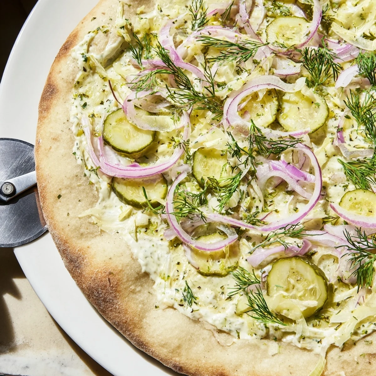 Creamy Pickle Pizza topped with mozzarella, dill, and vibrant red onions.  