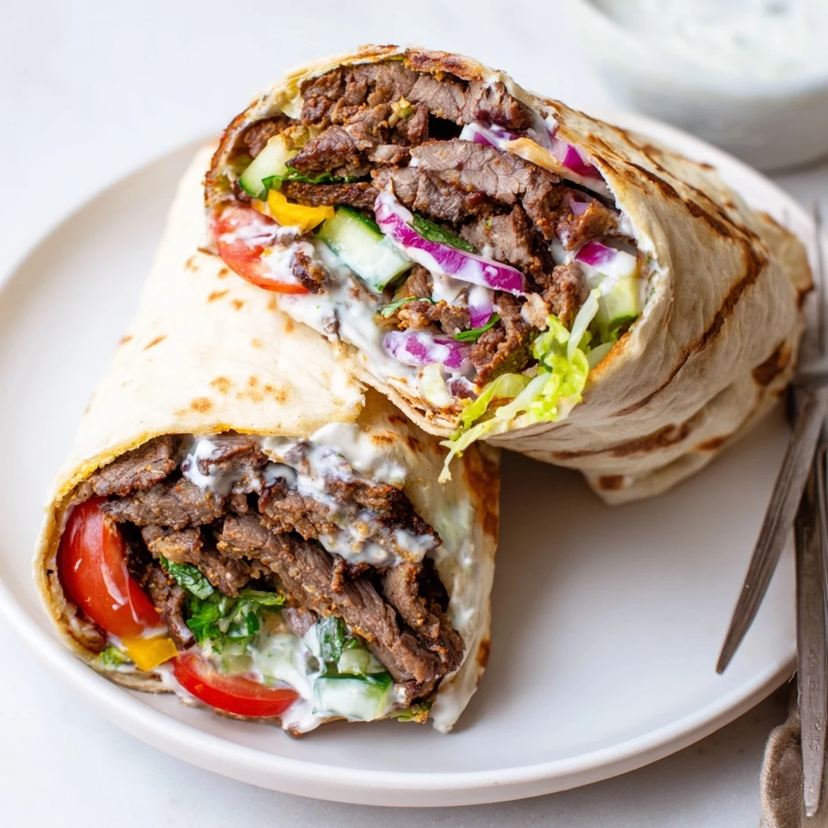 Savory beef shawarma wrapped in flatbread, drizzled with tangy yogurt sauce.  