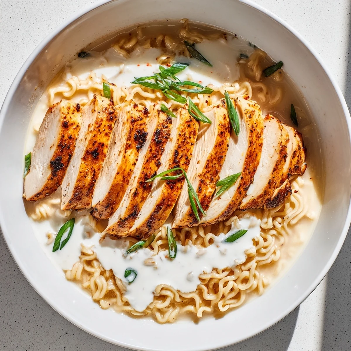 Steaming bowl of Fiery Chicken Ramen with tender chicken, creamy broth, and green onions, capturing bold flavors.