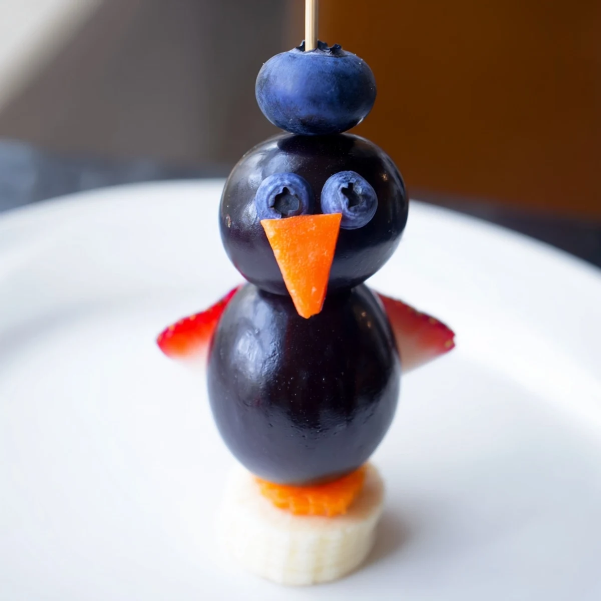 A playful Penguin Fruit Skewer Army displays mandarin orange feet below a cheerful berry assortment.