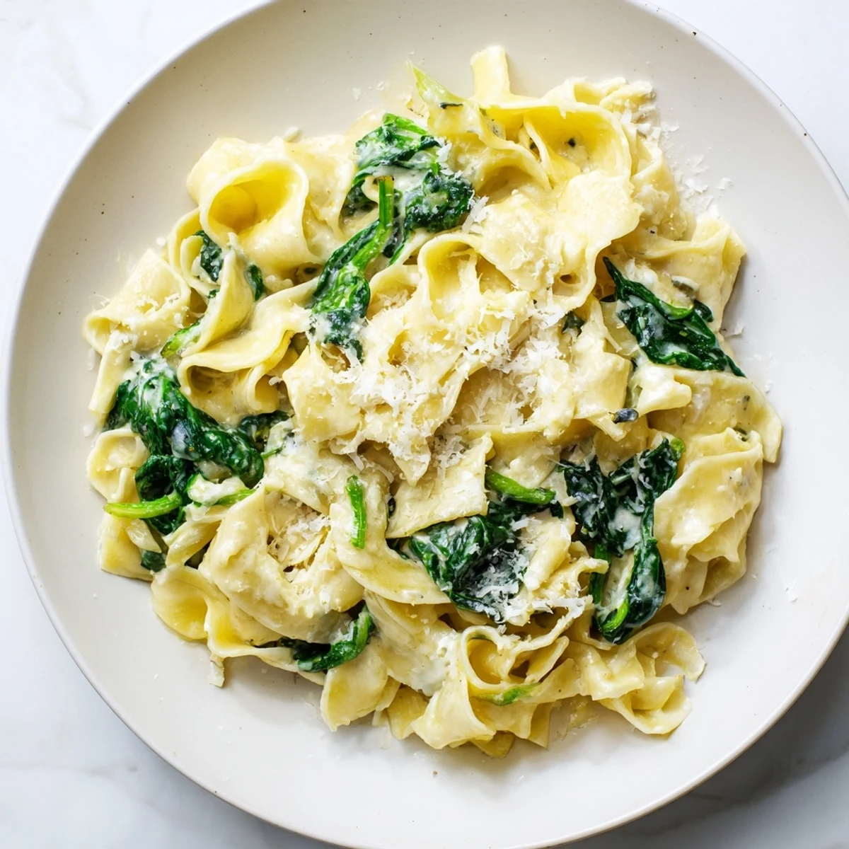 Creamy Spinach Garlic Noodles tossed in a velvety Parmesan sauce, with tender spinach and golden garlic in a warm skillet.  