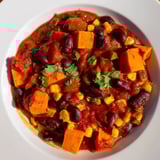 A close-up of hearty Smoky Sweet Potato Chili, showcasing chunky vegetables and a comforting, warm spice blend.