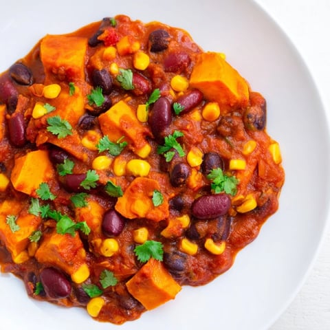 Steaming bowl of Smoky Sweet Potato Chili, filled with vibrant vegetables and a rich, smoky aroma.