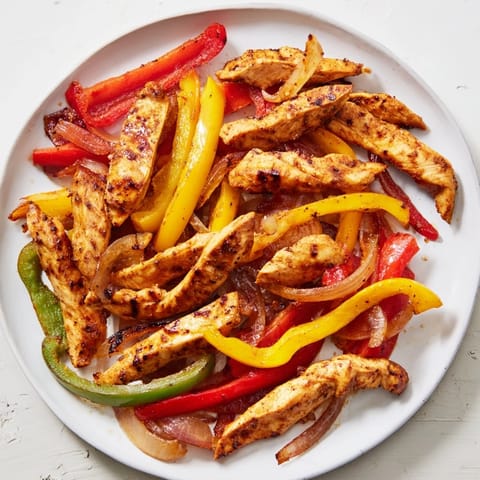 Golden-brown sheet-pan chicken fajitas, perfect with warm tortillas and fresh lime wedges, a tasty dinner.