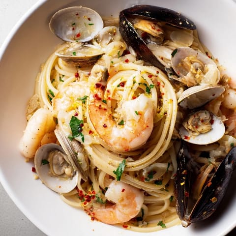A close-up of steaming seafood linguine, pasta glistening with olive oil and fresh herbs.