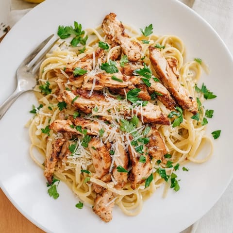 A close-up of Brown Butter Lemon Chicken Pasta shows nutty brown butter sauce clinging to spaghetti, chicken, and lemon zest.