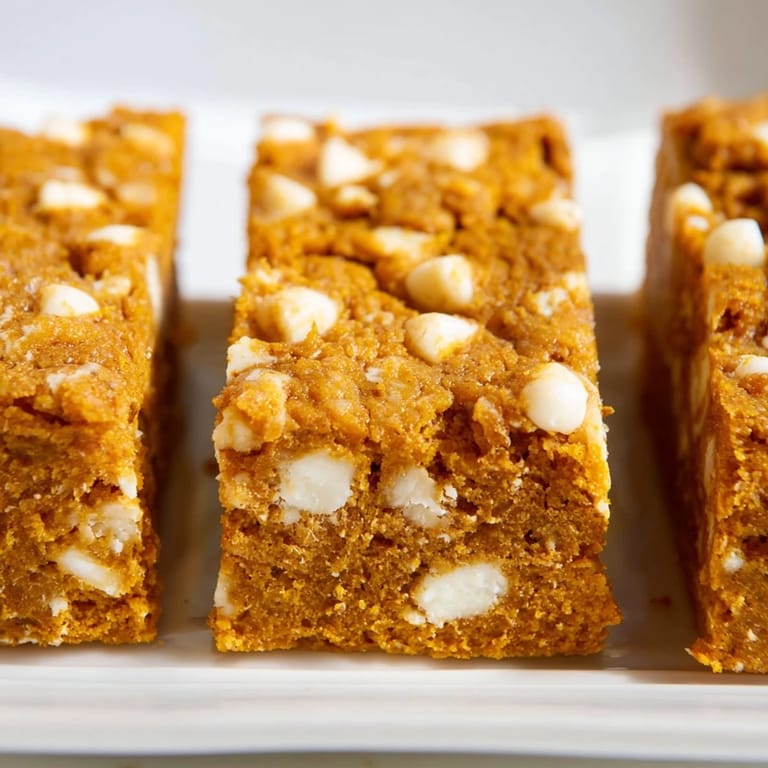 Decadent pumpkin white chocolate chip bars, warm and inviting, perfect for a cozy dessert.  