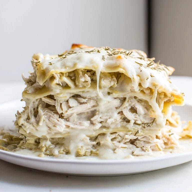 A close-up shot of steaming Rosemary Chicken Lasagna with layers of cheese and pasta.