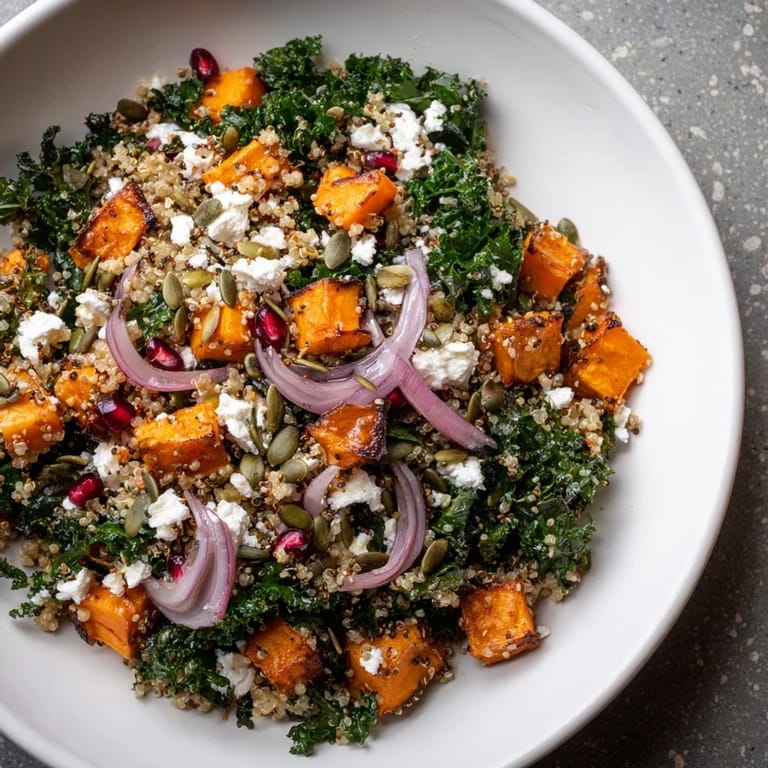Delicious Kale & Quinoa Salad topped with pomegranate seeds, and crumbled feta, perfect for a healthy meal.