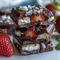 Viral Dubai Chocolate Strawberry Bark with pistachios, rose petals, and edible gold leaf on a marble countertop.